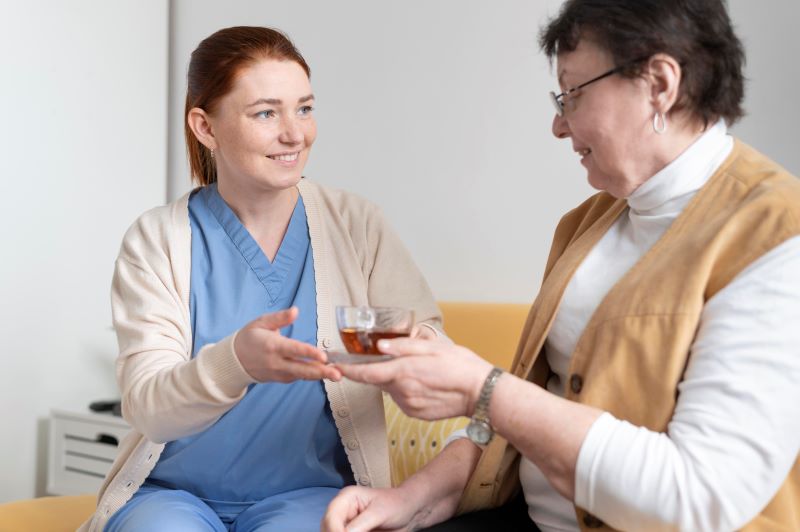Caregiver helping senior with tea
