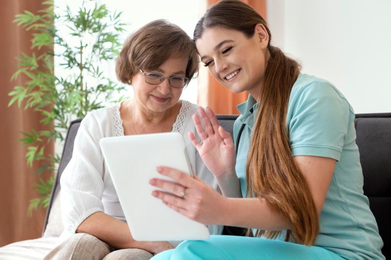 Senior reading with caregiver nearby